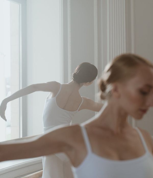 Woman performing a light, fluid movement in a calm studio setting.